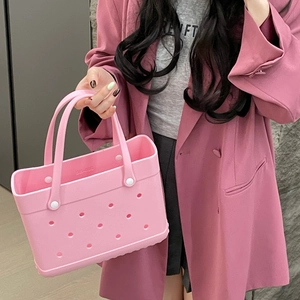 Close-up of pink EVA beach bag with white handles held by a model in a pink suit