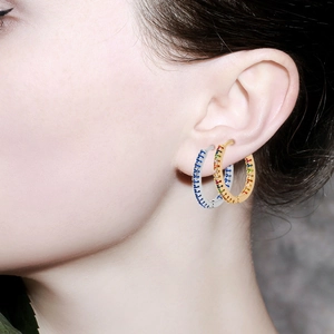 Close-up of sparkling 12mm hoop earrings with colorful zircon stones on model's ear