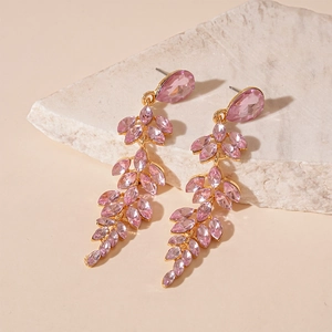 Detail of pink crystal leaf tassel earrings on stone with elegant gold metal base