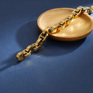 Close-up of golden geometric link chain bracelet with chunky pig nose clasp on tray