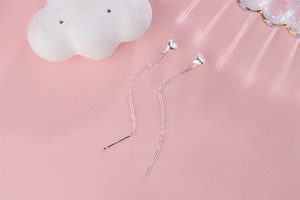 Detail view of S925 sterling silver long heart tassel earrings on pink background