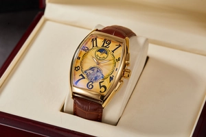 Detail of tonneau-shaped gold skeleton watch with moon phase on brown leather strap