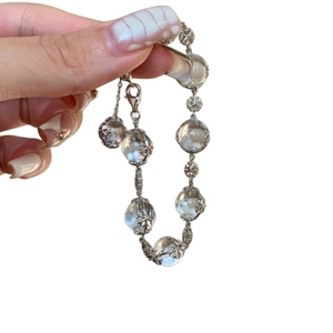 Elegant beaded crystal bracelet with silver snowflake charms on white background