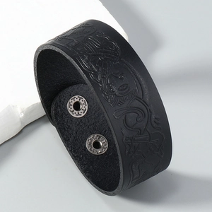 Detail of black leather wide cuff bracelet with embossed Celtic patterns and silver snaps