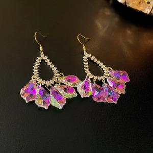 Golden flower earrings with purple crystals and sparkling diamonds on a textured background