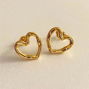 Detailed view of gold irregular textured heart stud earrings with lava style finish
