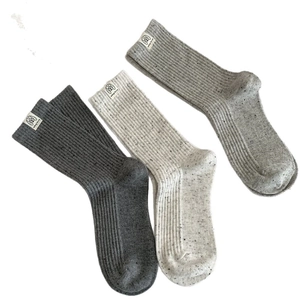 Three pairs of speckled knit crew socks in grey and beige colors with dog woven labels