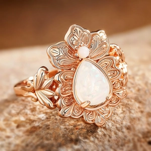 Macro view of rose gold floral ring with teardrop opal and intricate hollow petals