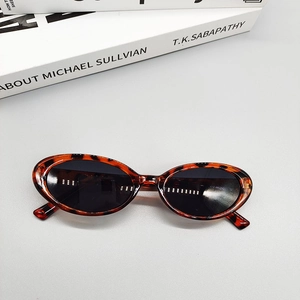 Top view of retro tortoiseshell oval sunglasses on a minimalist grey background