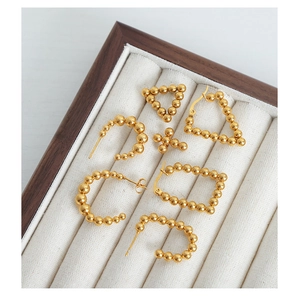 Detailed view of gold-plated beaded earrings in geometric shapes on jewelry tray