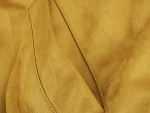 Primer plano de chaqueta bomber de ante amarillo con costuras finas y textura suave