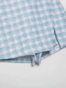 Close-up of textured tweed fabric in light green and purple plaid with fine stitching