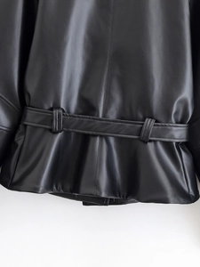 Detail shot of the back belt buckle and stitching on this black faux leather short jacket