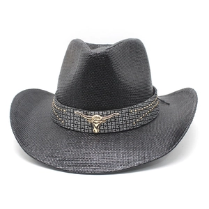 Detail of black straw cowboy hat with metallic bull head emblem and studded band decor