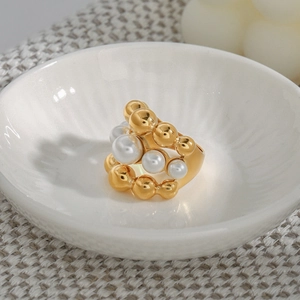 Elegant gold titanium steel ring with stacked white pearls on a ceramic dish