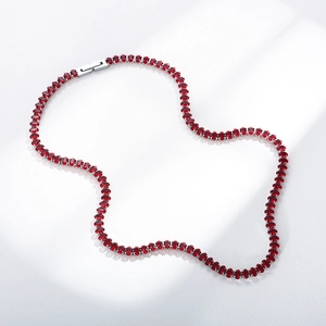 Close-up of silver-toned tennis necklace featuring oval-cut ruby-red gemstones