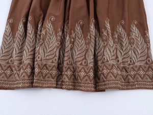 Broderie détaillée de feuilles beige sur l'ourlet plissé d'une robe longue marron