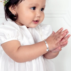 Detailed view of silver mesh ID bracelet and heart pendant set on infant model wrist