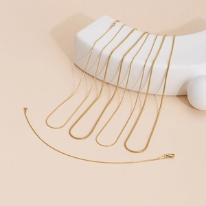Elegant gold snake chain necklaces displayed on minimalist white geometric props