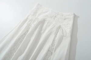 Detailed macro view of white lace skirt waist featuring floral embroidery and ribbon bows