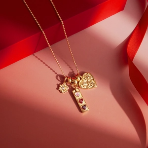 Detailed shot of 18K gold plated heart and daisy pendants on a gift box