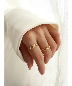 Detail of hollow chain design gold rings worn on fingers with soft fabric background