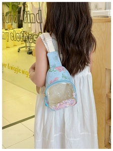 Girl wearing a light blue kids crossbody bag with glitter sequins and floral pattern