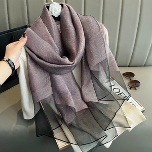 Detail of silk scarf in grey-purple with black mesh and a white camellia flower brooch