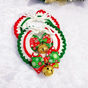 Close-up of hand-knitted Christmas pet bibs with gold bells and snowflake ribbons