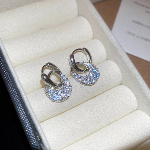 Close-up of sparkling zircon water drop C-shaped earrings in a white velvet jewelry box