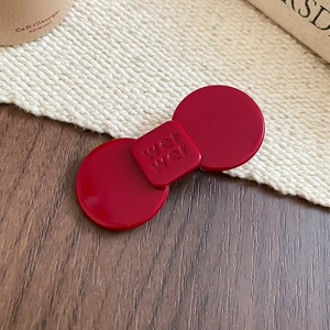 Close-up of a red resin flower hair clip with wer wer engraving on wooden background