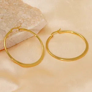 Minimalist gold hoop earrings for women on elegant champagne silk and stone backdrop