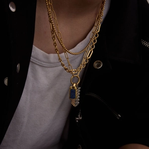 Detail of layered gold necklaces with blue lapis lazuli pendant and silver feather charm