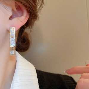Detail of silver drop earrings with rectangular and square cubic zirconia stones on model