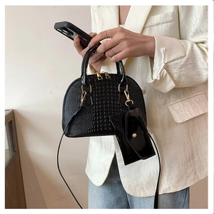 Detail of a black crocodile pattern shell bag with a matching mini pouch and gold hardware