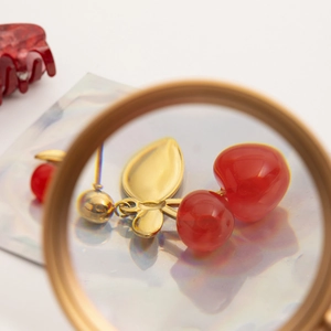 18K gold stainless steel cherry drop earrings with red fruits shown through a magnifying glass