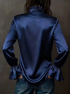 Detail of elegant dark blue satin shirt featuring a ruffle collar and bell sleeves back view