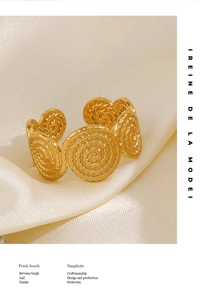 Macro detail of golden spiral textured adjustable stainless steel ring on silk background