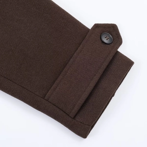 Detail of dark brown wool coat sleeve featuring adjustable cuff strap and black button