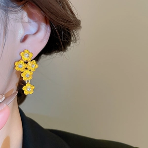 Detailed close-up of golden floral drop earrings with sparkling zircon center stones
