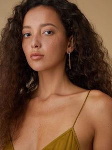 Detailed close-up of a long teardrop earring with wood grain and white shell finish on model