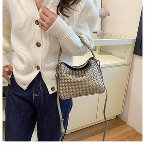 Detail shot of the metallic woven texture and handle of the champagne gold crossbody bag