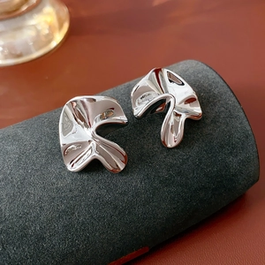 Close-up of silver stud earrings featuring an irregular folded and twisted metal design