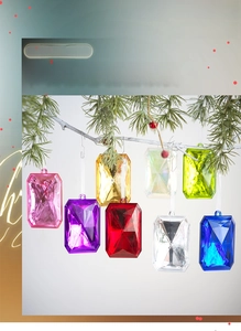 Close-up of multicolored acrylic faceted gemstone ornaments hanging on a Christmas tree branch