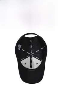 Internal detail of black cotton baseball cap showing FBXS seams and adjustable strap