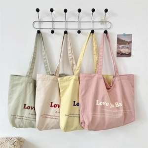 Detailed display of four colorful canvas tote bags in pastel green, cream, yellow, and pink