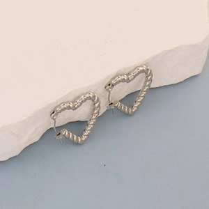 Close-up of silver heart hoop earrings with twisted rope texture on stone display