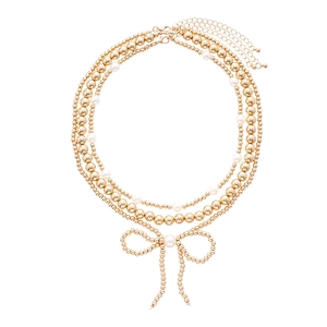 Three-layer beaded necklace with gold beads, white pearls, and a bow pendant
