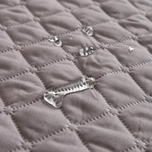 Waterproof quilted grey pet bed mat with diamond pattern and water droplets on surface