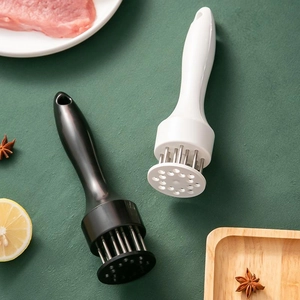 Black and white stainless steel meat tenderizers with needle blades on kitchen background